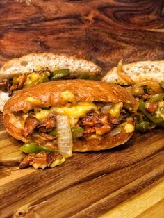 two sandwiches with meat, cheese and peppers on a cutting board next to some bread