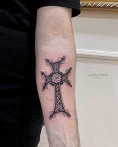 a man's arm with a cross tattoo on it