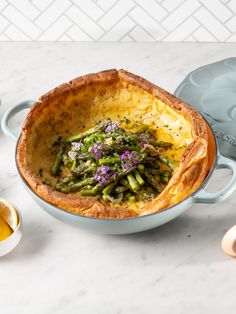 asparagus and cheese quiche in a blue dish on a white marble table