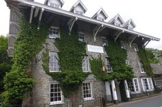 an old stone building with ivy growing on it's side and windows in the front