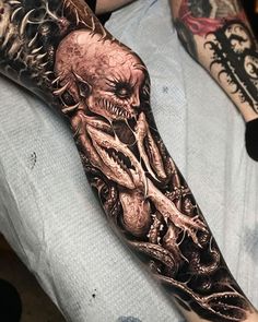 a man's arm covered in tattoos with an image of a demon on it