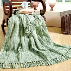 a green blanket sitting on top of a wooden rocking chair next to a basket filled with books