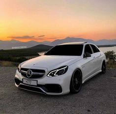 a white car parked on top of a dirt field next to a body of water