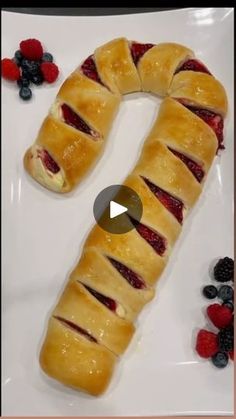 a pastry shaped like the number 2 on a plate with berries and raspberries