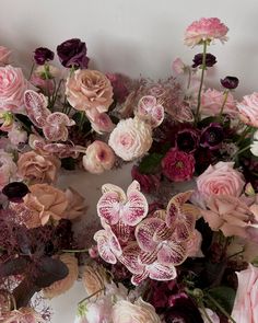 an arrangement of pink and purple flowers on a white background