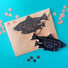 two fish magnets on top of an envelope with confetti scattered around them