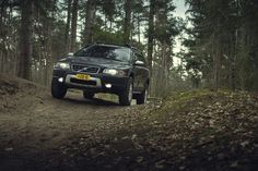 a black car driving down a dirt road in the woods