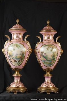 two pink and gold vases sitting side by side on black clothed background with golden trimming