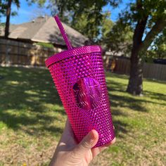 a person holding up a pink cup in their hand