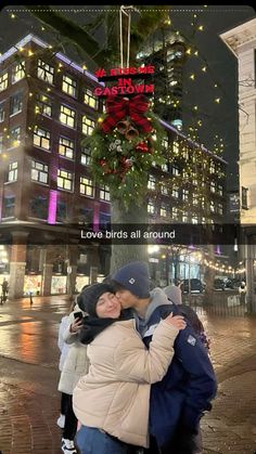 two people hugging each other in front of a christmas tree with lights on it and the words love birds all around