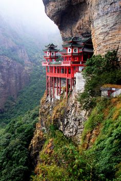 a red building sitting on the side of a cliff