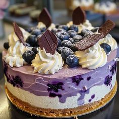 a cake with blueberries, cream and chocolate on top is sitting on a table