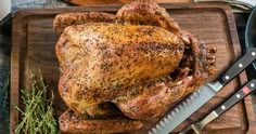 a whole chicken on a cutting board with a knife and other cooking utensils