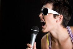 a woman singing into a microphone wearing sunglasses