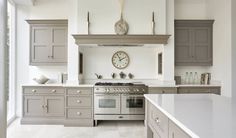 a kitchen with gray cabinets and a large clock on the wall above the stove top