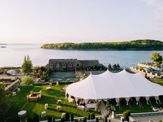 an aerial view of a tent set up on the lawn next to a body of water