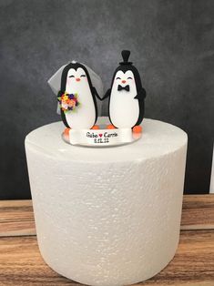 two penguins are standing on top of a roll of toilet paper and one is wearing a bow tie