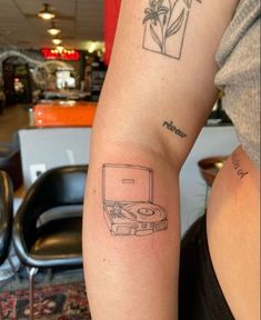 a woman with a tattoo on her arm has a record player in front of her