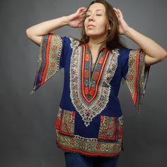 "Bright dashiki print shirt in rainbow colors on blue background. Made of cotton fabric, has wide 3/4 sleeves, side slits and notched neckline. Hippie style shirt. Two front pocket. Excellent vintage conditions. Fabric: 100% cotton Size: app. S / M but please check measurements of hips/ model M size ✂------m e a s u r e m e n t s-------------- Bust and waist already doubled. Bust: 39\" 99 cm Waist : 39\" 99 cm Hips: 39,5\" 100 cm Length: 28,5\" 72 cm Best way to know if it will fit? Compare the Multicolor Batik Print Short Sleeve Top, Multicolor Short Sleeve Tops With Batik Print, Bohemian Multicolor Blouse With Vintage Print, Bohemian V-neck Blouse With Graphic Print, Bohemian Graphic Print Short Sleeve Blouse, Bohemian Blouse With Graphic Print And Short Sleeves, Bohemian Short Sleeve Blouse With Graphic Print, Blue Casual Short Sleeve Kaftan, Blue Bohemian Short Sleeve Tops