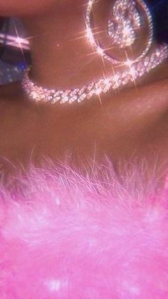 a close up view of a woman's breast with pink feathers and diamond jewelry