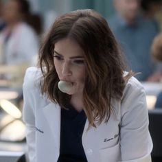 a woman sitting at a table with a piece of food in her mouth