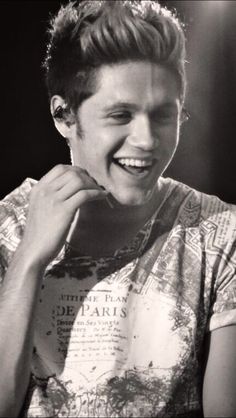 a black and white photo of a young man smiling with his hand on his chin