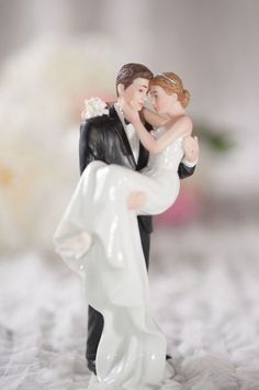 a wedding cake topper with a bride and groom figurine holding each other