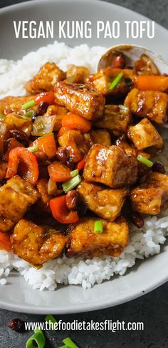 a white plate topped with chicken and vegetables next to rice on top of a table