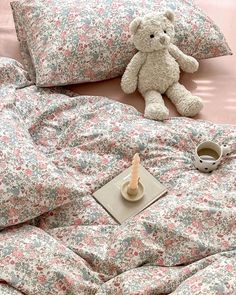 a teddy bear sitting on top of a bed next to pillows and a pillow case