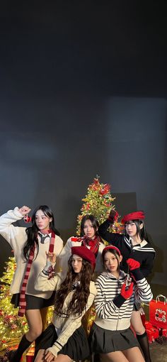 the girls are posing in front of christmas tree