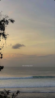 the sun is setting over the ocean with waves coming in from the water and trees on the shore