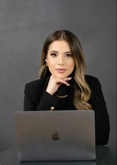 a woman sitting in front of a laptop computer with her chin resting on her hand