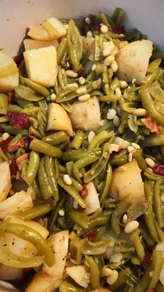 green beans and potatoes are mixed together in a white bowl with seasoning sprinkled on top