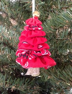 a red christmas tree ornament hanging from a pine tree