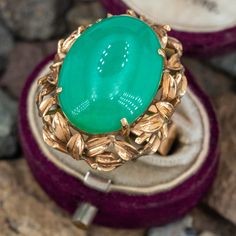 This gorgeous vintage cocktail ring features a centered oval cabochon chrysoprase that is decorated with a gold border of sticks and leaves. The ring is crafted in 18k yellow gold with a nice patina and is currently a size 7.75. Luxury Green Chrysocolla Rings, Elegant Green Opal Ring Oval Cabochon, Elegant Green Opal Ring With Oval Cabochon, Elegant Oval Chrysoprase Rings, Yellow Gold Emerald Chrysoprase Cabochon Ring, Elegant Green Cabochon Opal Ring, Yellow Gold Chrysoprase Cabochon Ring, Antique Yellow Gold Cabochon Emerald Ring, Antique Yellow Gold Emerald Cabochon Ring