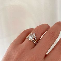 a woman's hand with a diamond ring on top of her finger and an engagement band