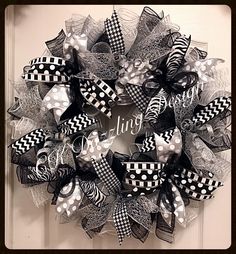 a wreath with black and white bows hanging on the front door for someone's house