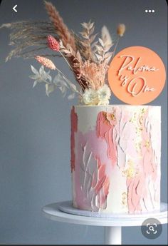 there is a pink and white cake with flowers on the top it has an orange sign that says please to go