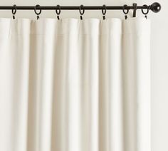 a white curtain hanging from a metal rod with black hardware on it's end