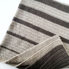 a close up of a knitted tie on a white tablecloth with black and grey stripes