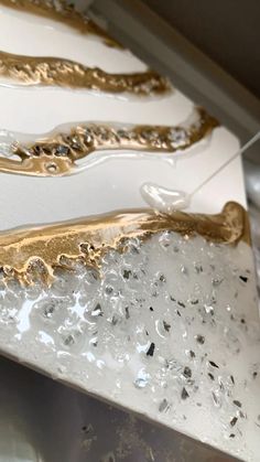 some gold and silver items on display in a glass case with water droplets running down them