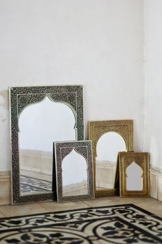 three mirrors sitting next to each other on top of a rug in front of a wall