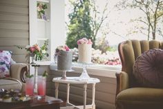 a living room filled with furniture and flowers in vases on top of the windowsill