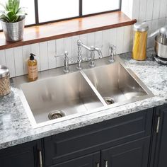 a kitchen sink with marble counter tops and black cabinets