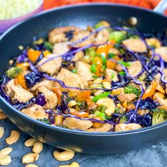 a pan filled with chicken, broccoli and cashews on top of a table