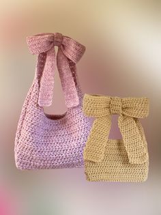 two crocheted purses with bows hanging from the handles, one pink and one yellow