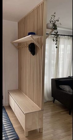 a wooden shelf with a hat on it next to a black chair and window in the background