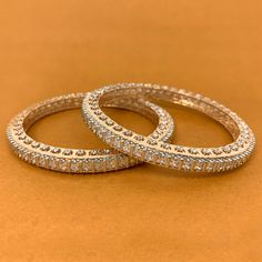 Unique and Stunning, American Diamond stone bangles. These bangles are in a rosegold-tone and will match a variety of outfits. You can wear them with formal traditional outfits, western outfits, or even informal casual gatherings. Best for gifting or for personal use, wear it to any occasion and be the spotlight. Eye-catching and unique jewelry that will set you apart. Gift this piece to a loved one, and see their face light up with joy. Elegant Festive Stackable Jewelry, Formal Rose Gold Bangle With Hand Set Detail, Formal Rose Gold Bangle With Hand Set, Rose Gold Round Bracelet For Festive Occasion, Rose Gold Round Bracelets For Festive Occasion, Elegant Stackable Bangle For Festive Occasions, Rose Gold Stackable Bangle For Wedding, Stackable Rose Gold Bangle For Wedding, Elegant Rose Gold Bracelets For Festive Occasions