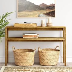 two baskets under a table with a painting on the wall above it and a rug underneath