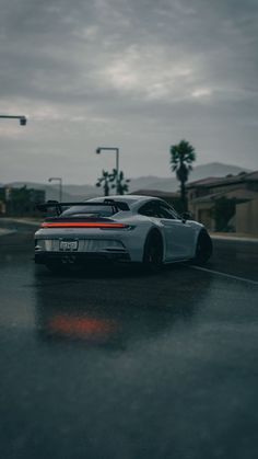 a white sports car parked on the side of a road next to a street light